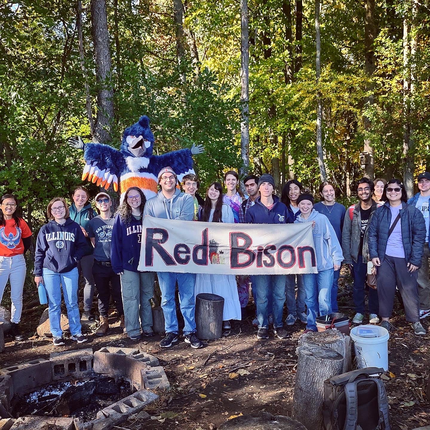 The Belted Kingfisher posing behind a group of students with a banner that reads "Red Bison"