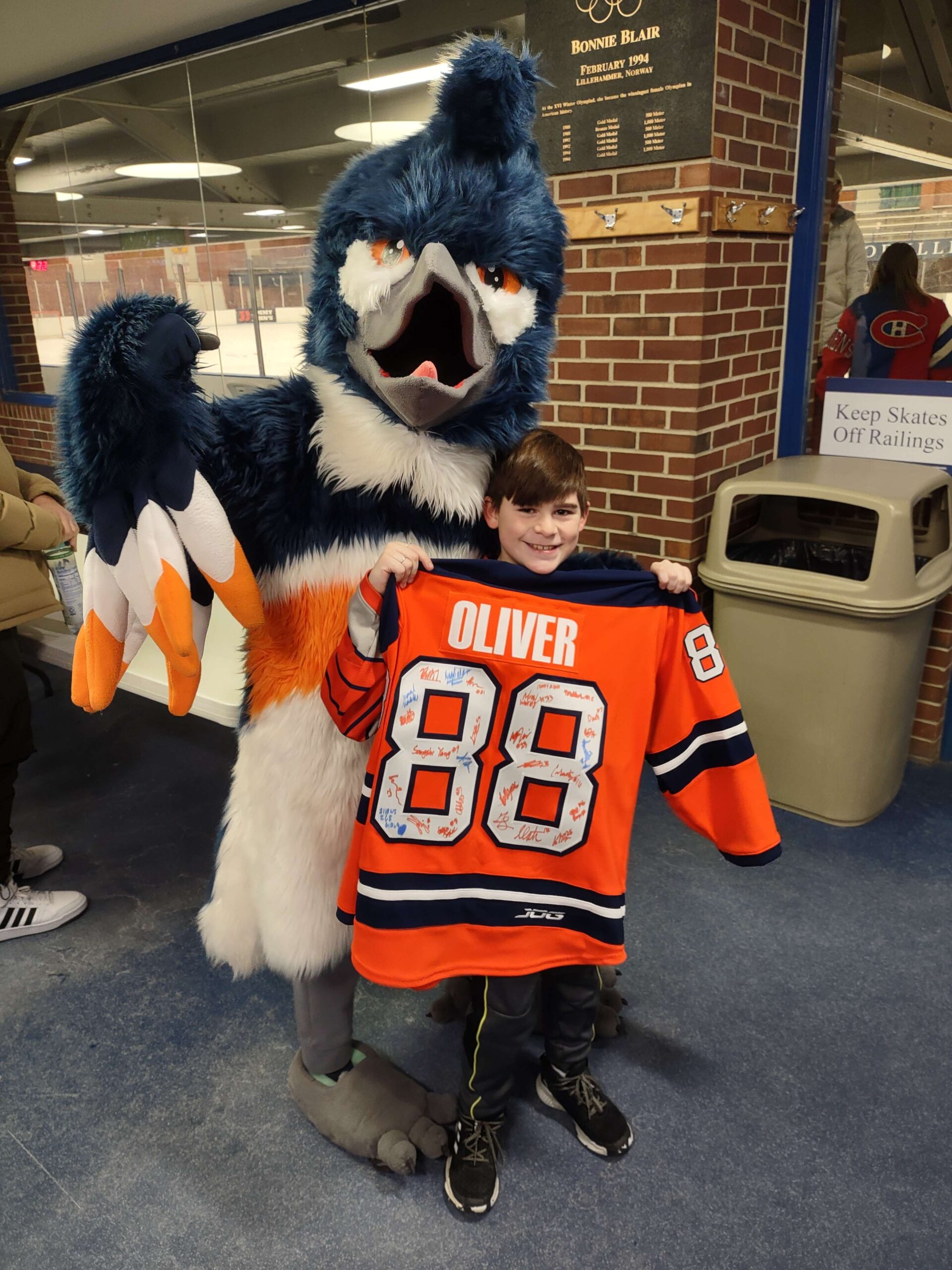 The Belted Kingfisher posing with a boy holding up an ice hockey jersey that reads "Oliver 88"