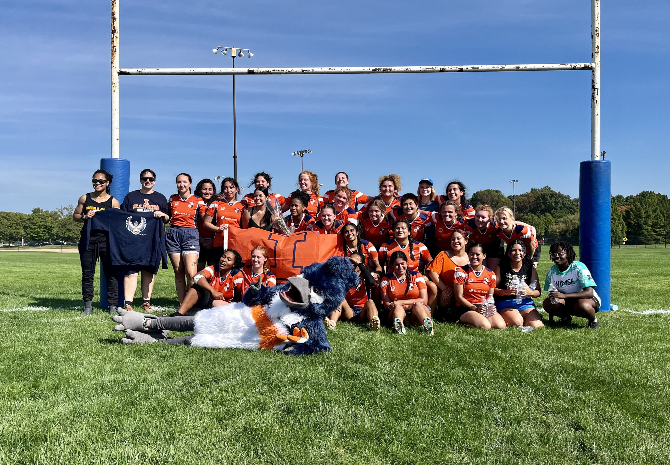 The Belted Kingfisher mascot posing together with the woman's rugby team