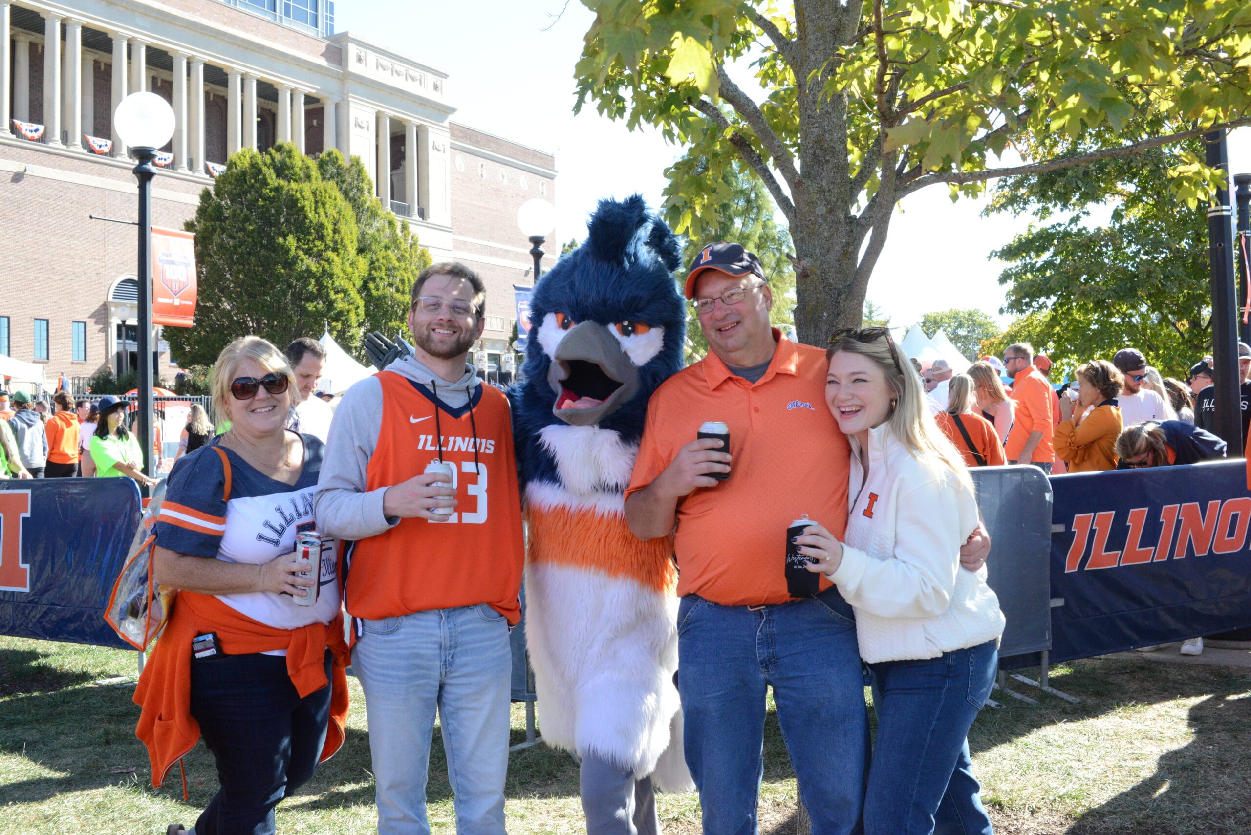 The Belted Kingfisher mascot posing together with four adults wearing University of Illinois merchandise