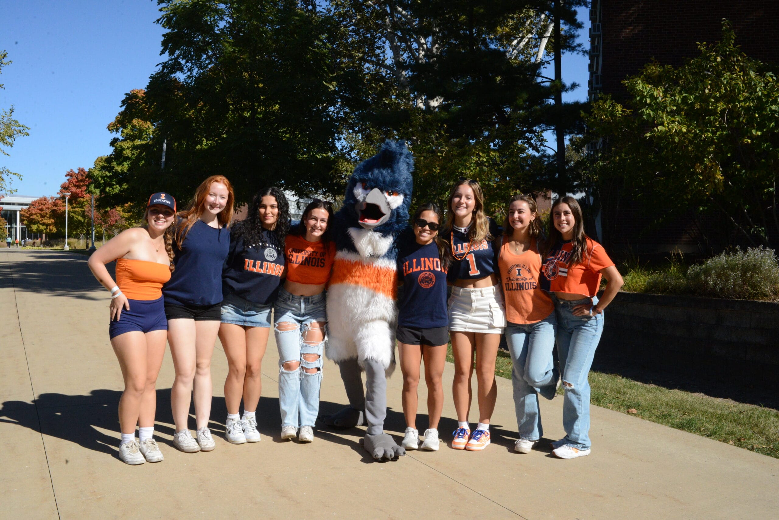 The Belted Kingfisher mascot posing together with eight students wearing University of Illinois merchandise