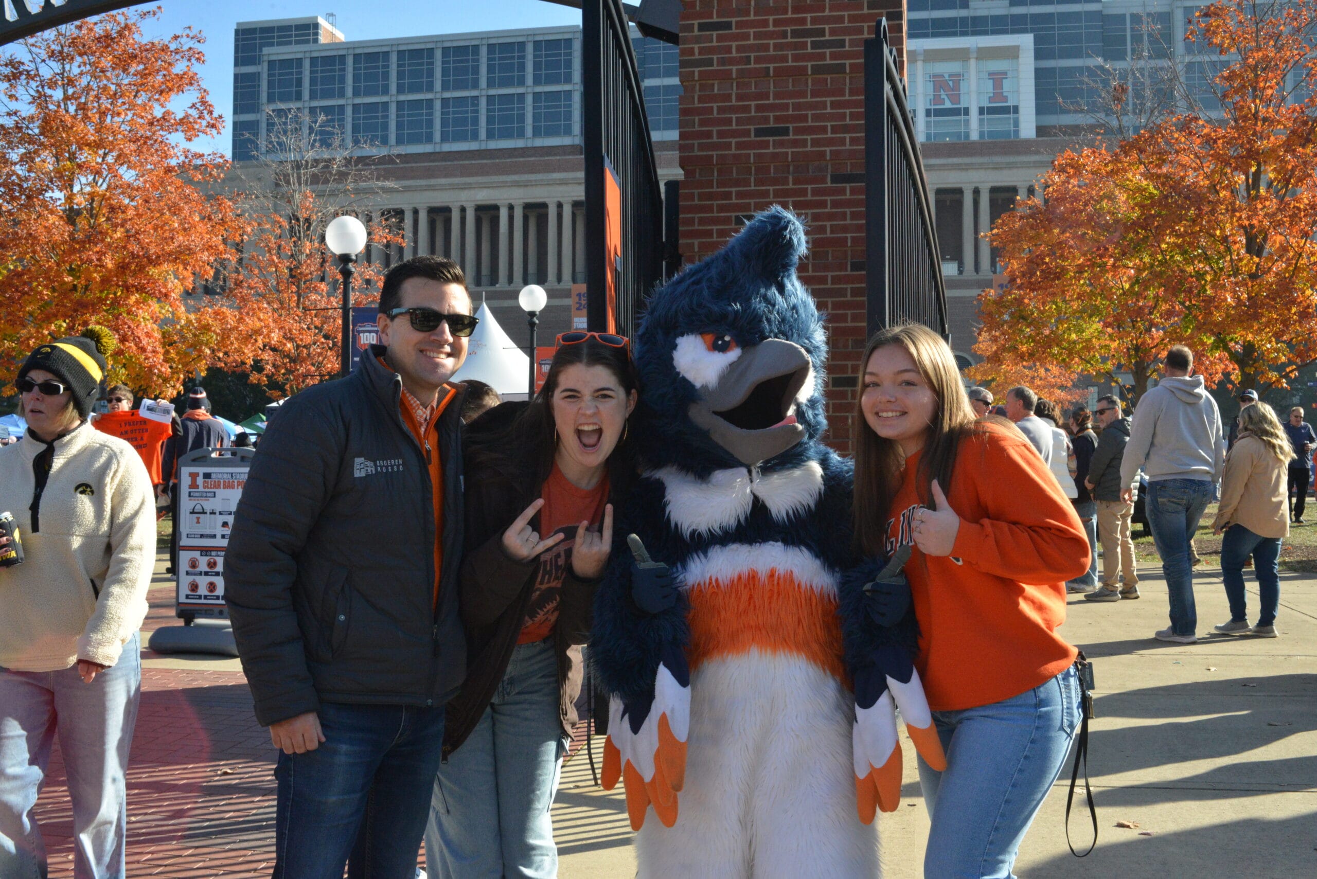 The Belted Kingfisher mascot posing together with three adults wearing University of Illinois merchandise