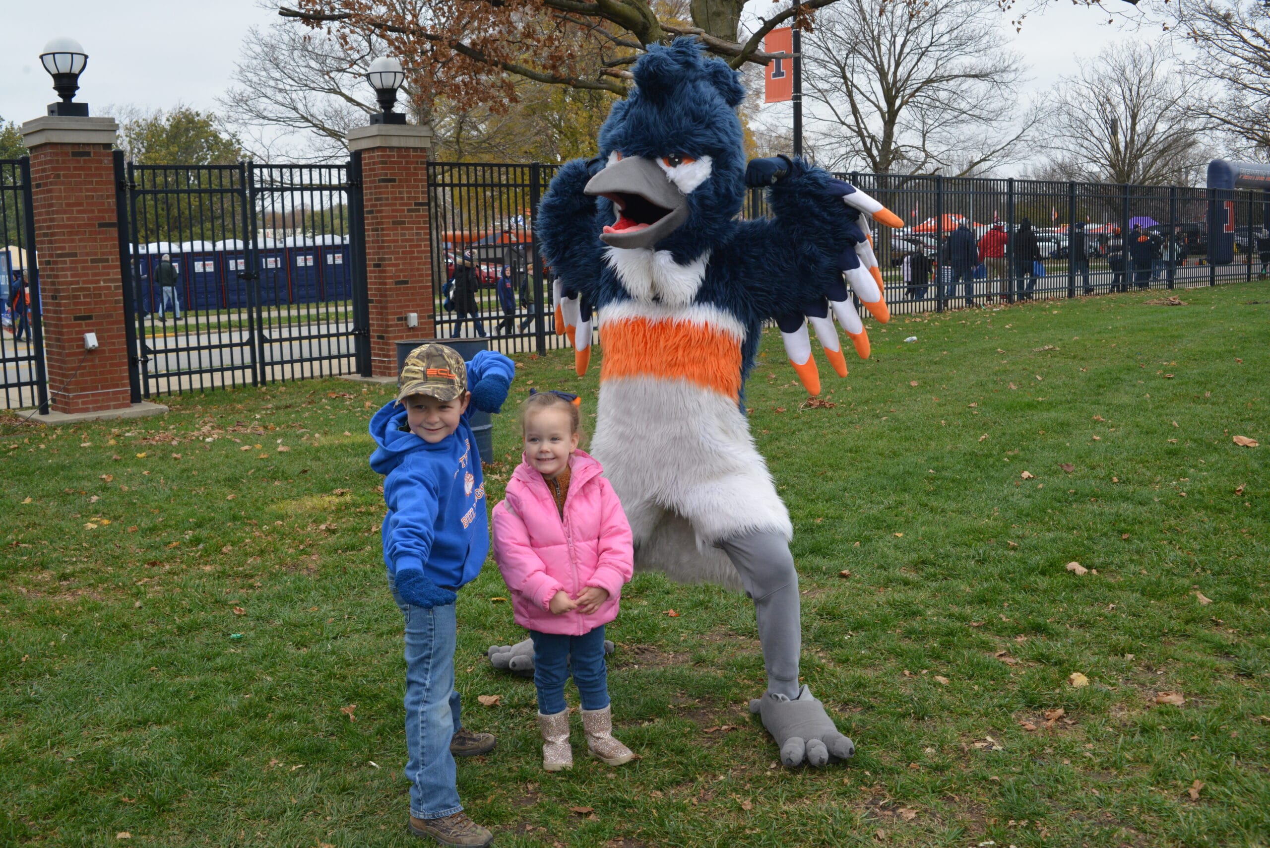 The Belted Kingfisher mascot posing together with two children