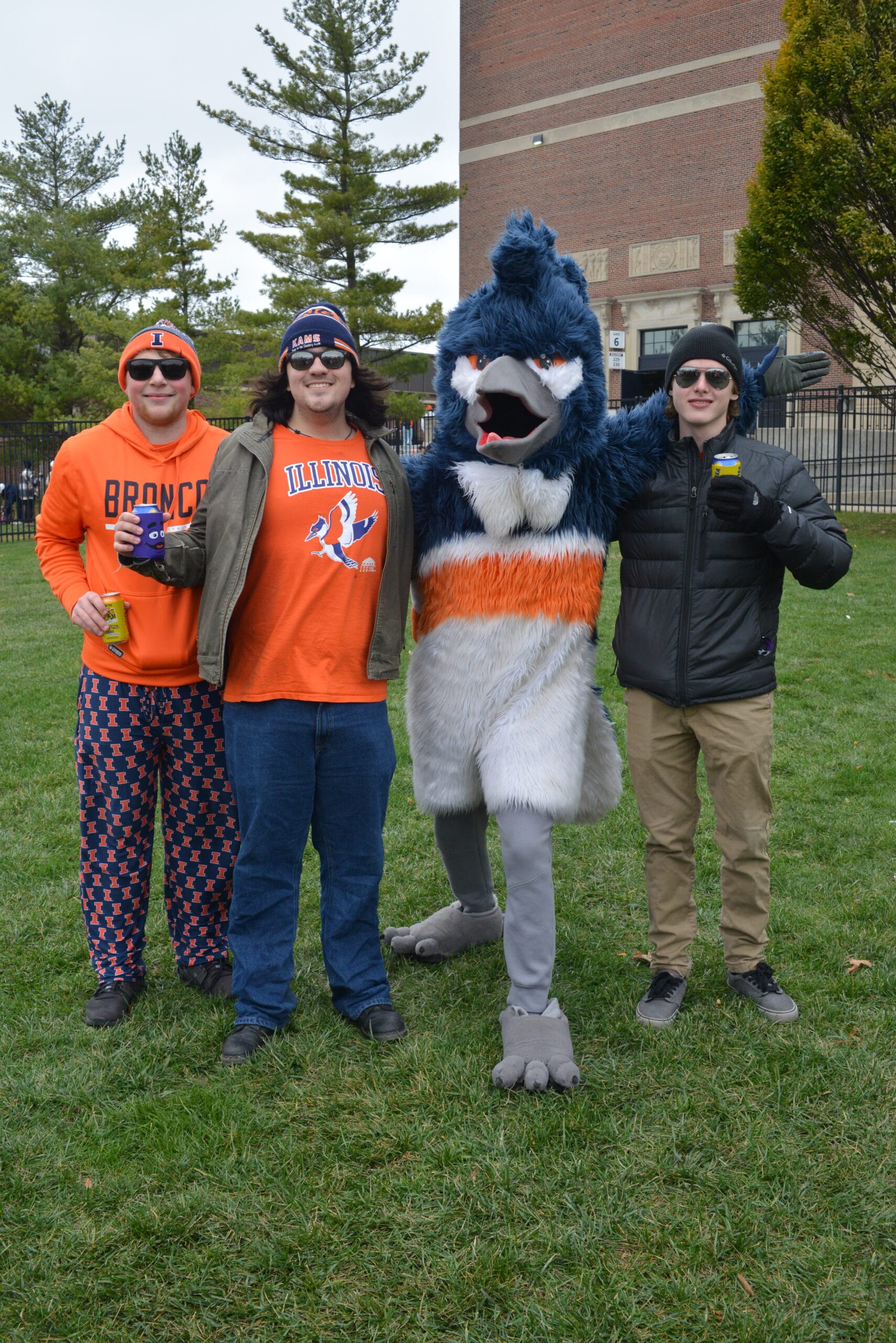 The Belted Kingfisher mascot posing together with three adults, one of whom is wearing Belted Kingfisher merchandise