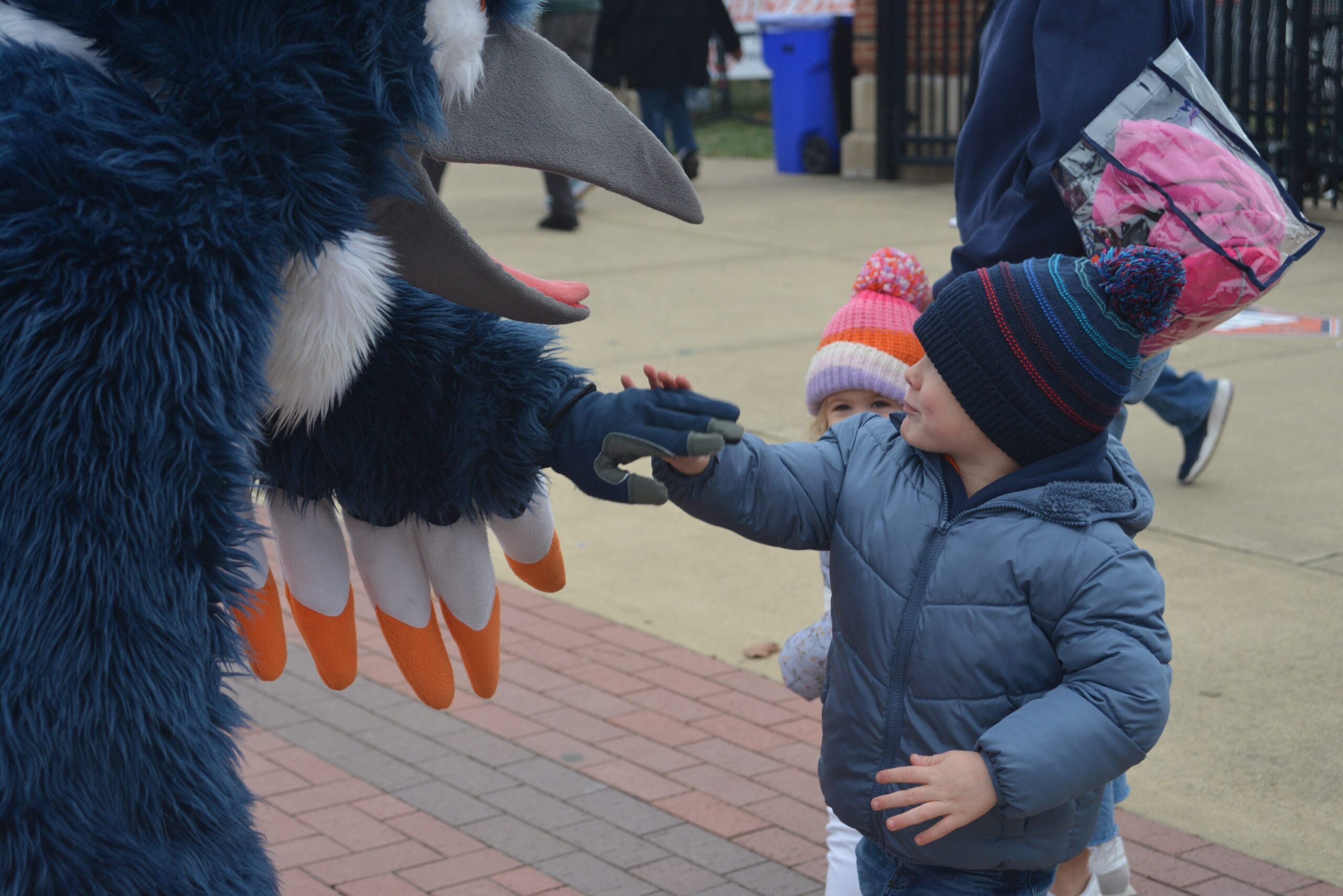The Belted Kingfisher mascot and a boy having a high five