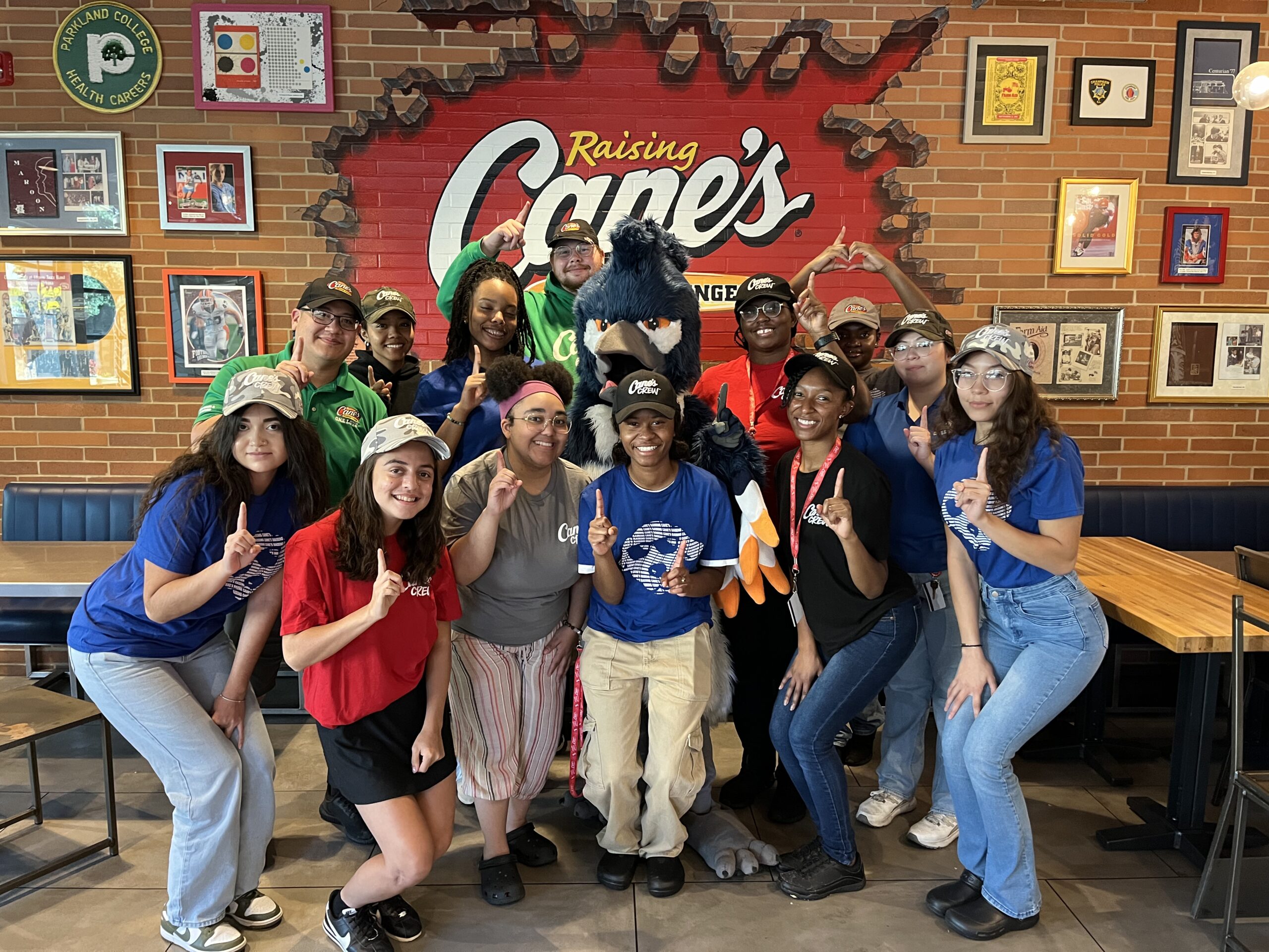 The Belted Kingfisher mascot posing together with employees of Raising Cane's