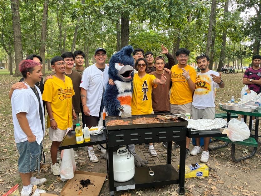 The Belted Kingfisher mascot posing together with the members of the Lambda Upsilon Lambda at a barbecue
