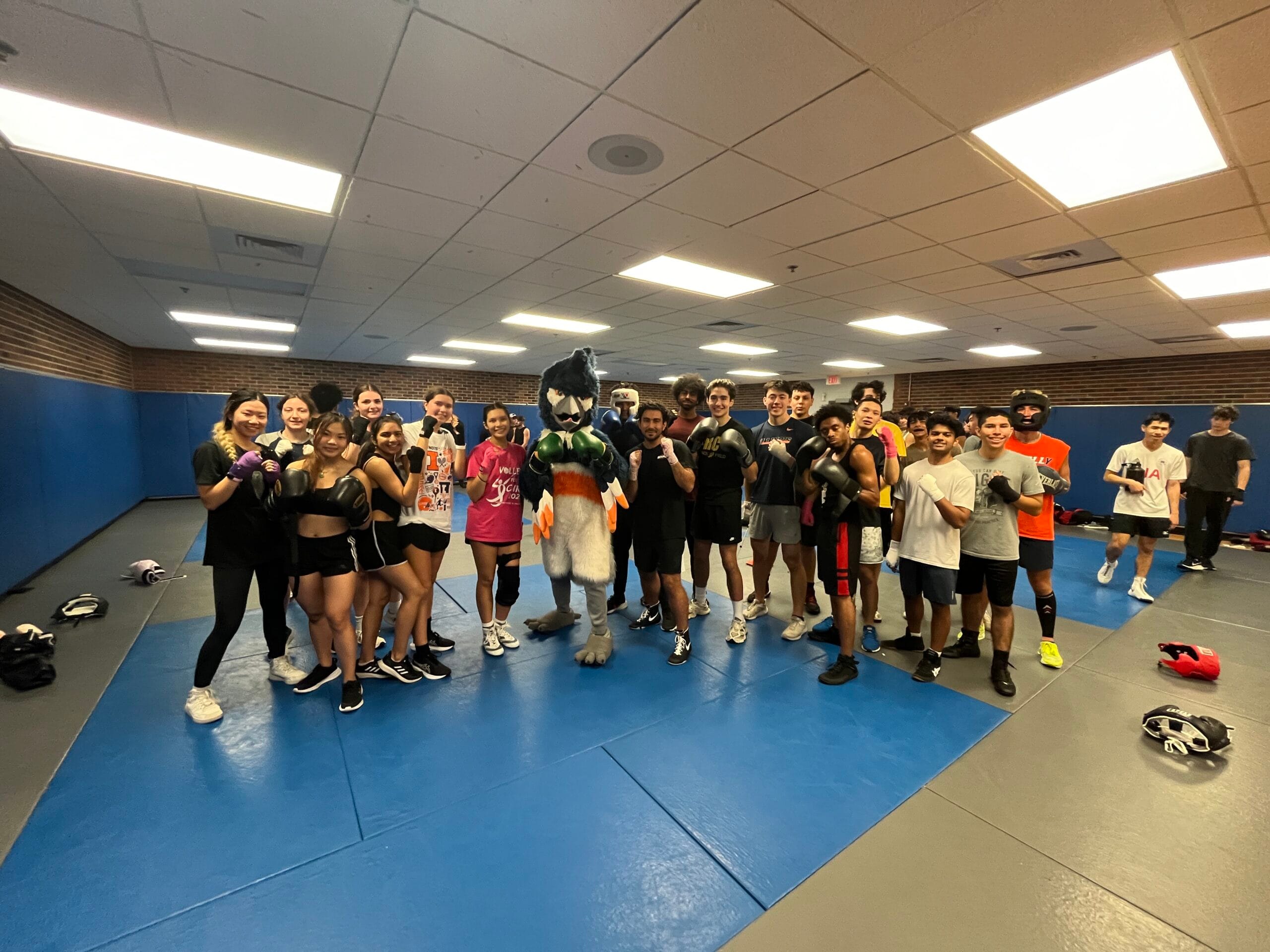 The Belted Kingfisher mascot posing together with members of the Illini Boxing Club in the Combat Room