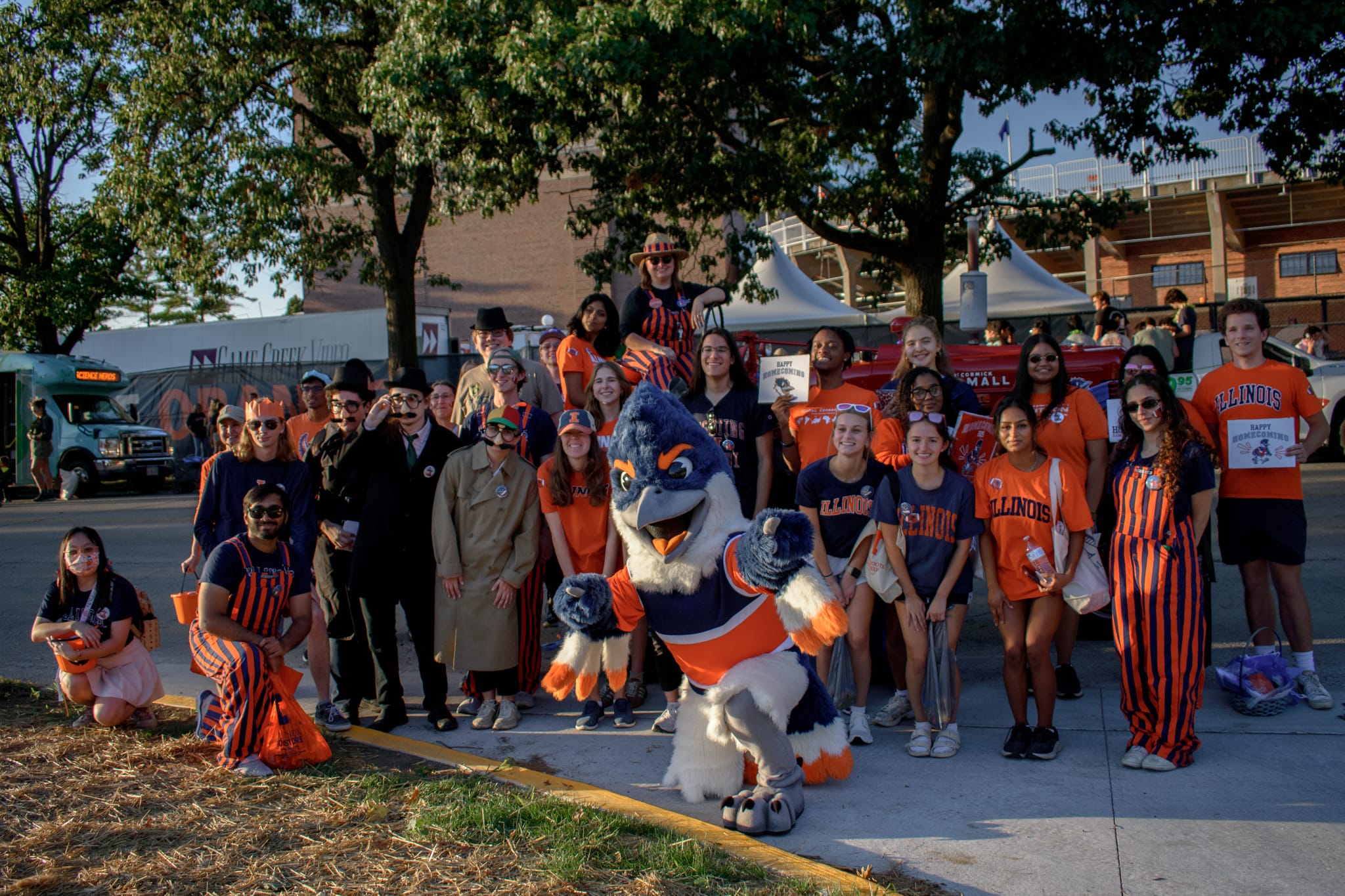 Belted Kingfisher and multiple students posing in front of a red tractor at the Homecoming Parade