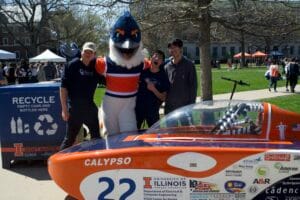 Belted Kingfisher posing with three students behind the Calypso solar car