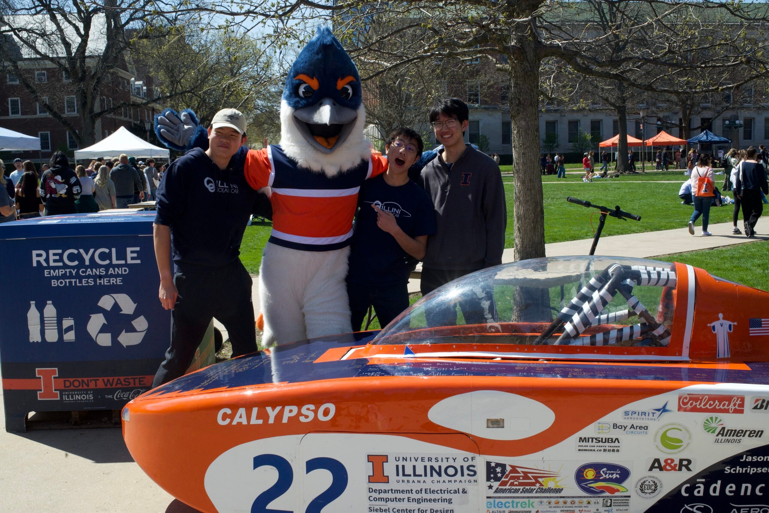 Belted Kingfisher posing with three students behind the Calypso solar car