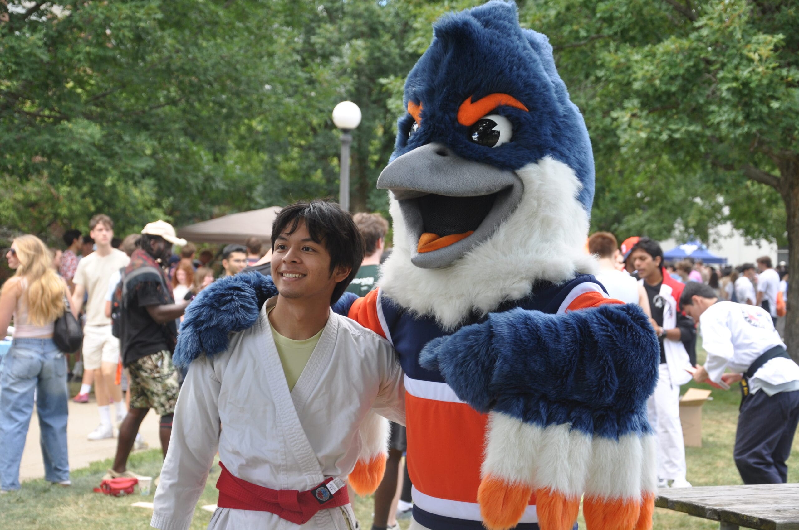 Belted Kingfisher posing with a student in martial arts attire with a red belt