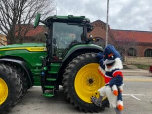 Belted Kingfisher posing next to the wheel of a John Deere tractor