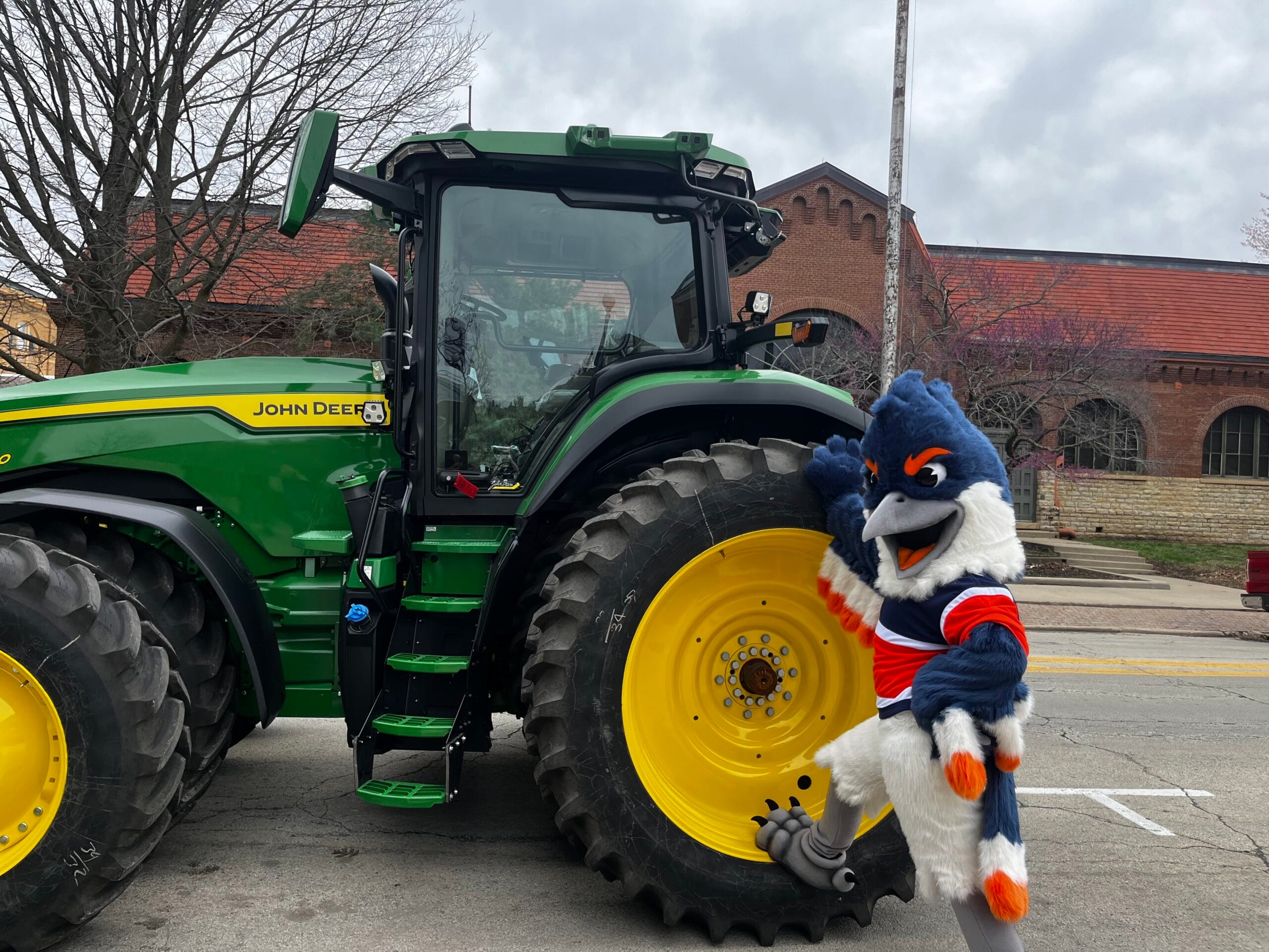 Belted Kingfisher posing next to the wheel of a John Deere tractor