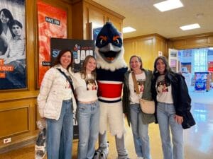 Four people in white shirts and jeans posing together with the Belted Kingfisher