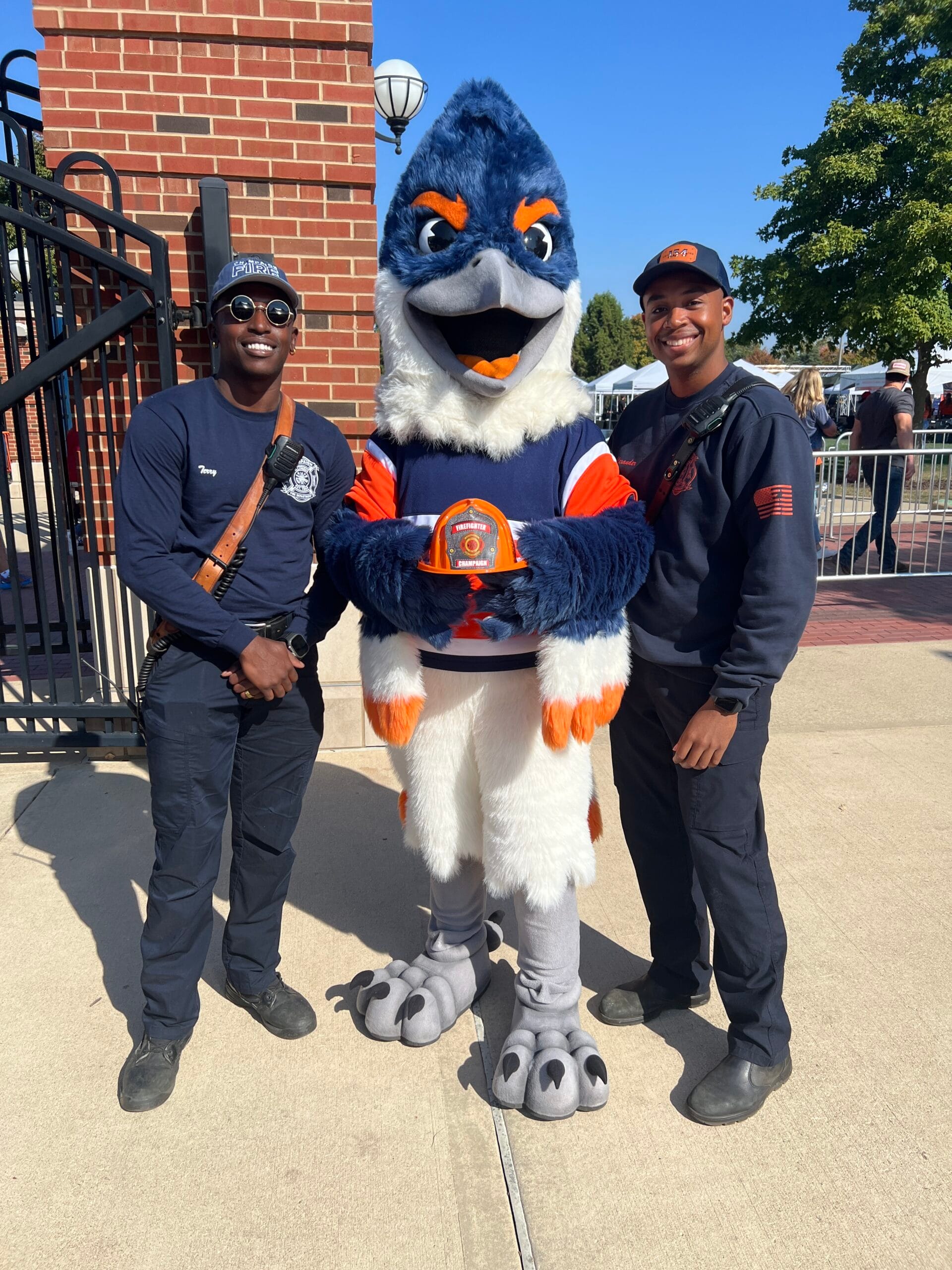 Belted Kingfisher with two firefighters, holding up a firefighter hat