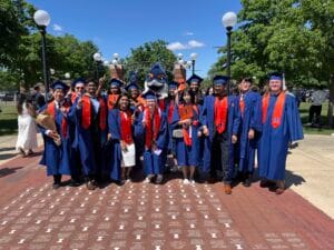 Belted Kingfisher posing together with students in graduation regalia