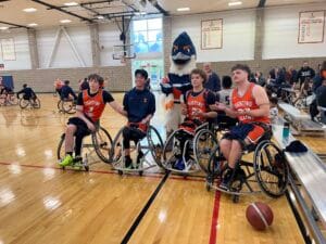 Belted Kingfisher posing with four members of the University of Illinois Urbana-Champaign men's wheelchair basketball team