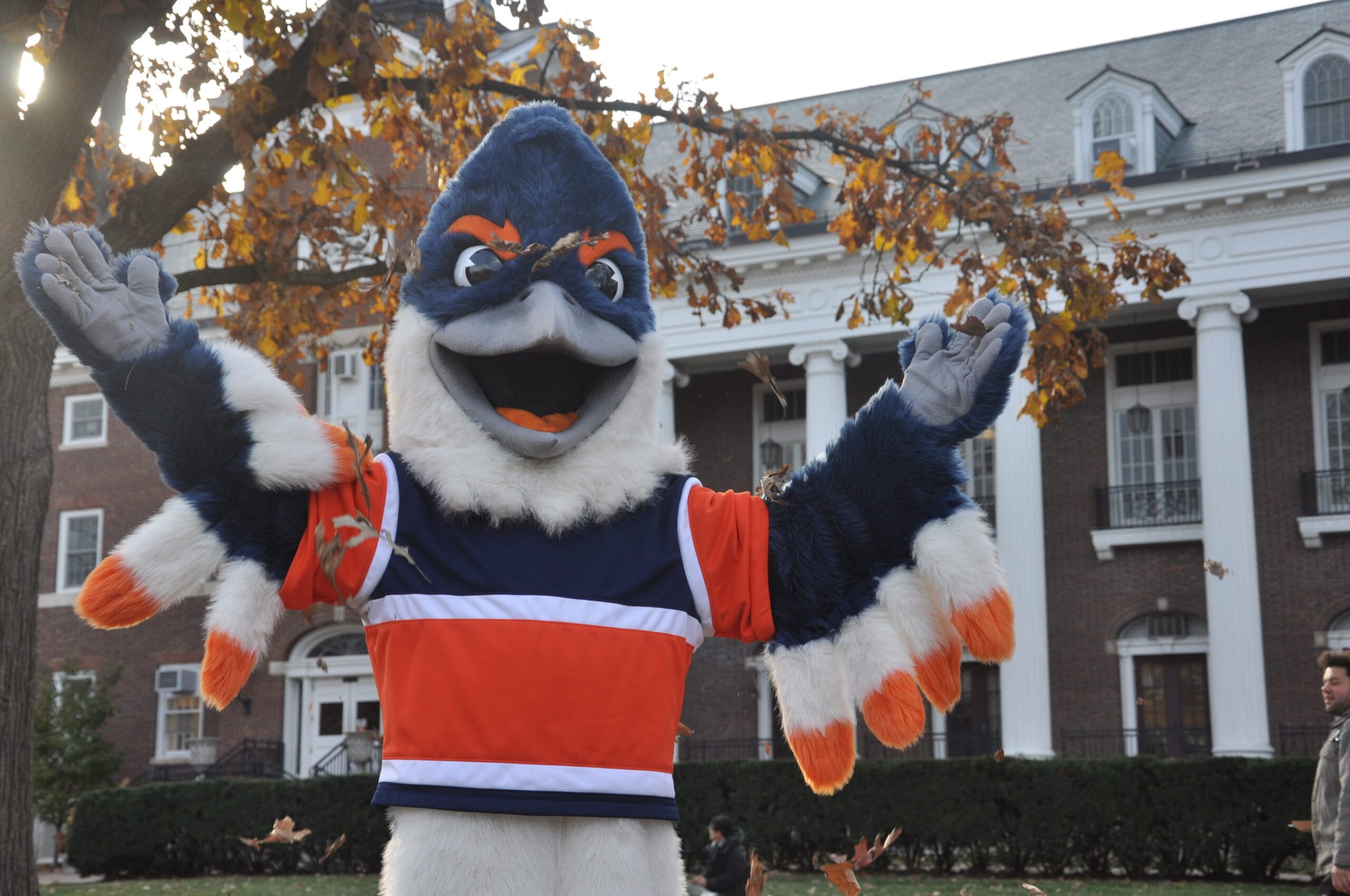 The Belted Kingfisher mascot tossing fall leaves in the air