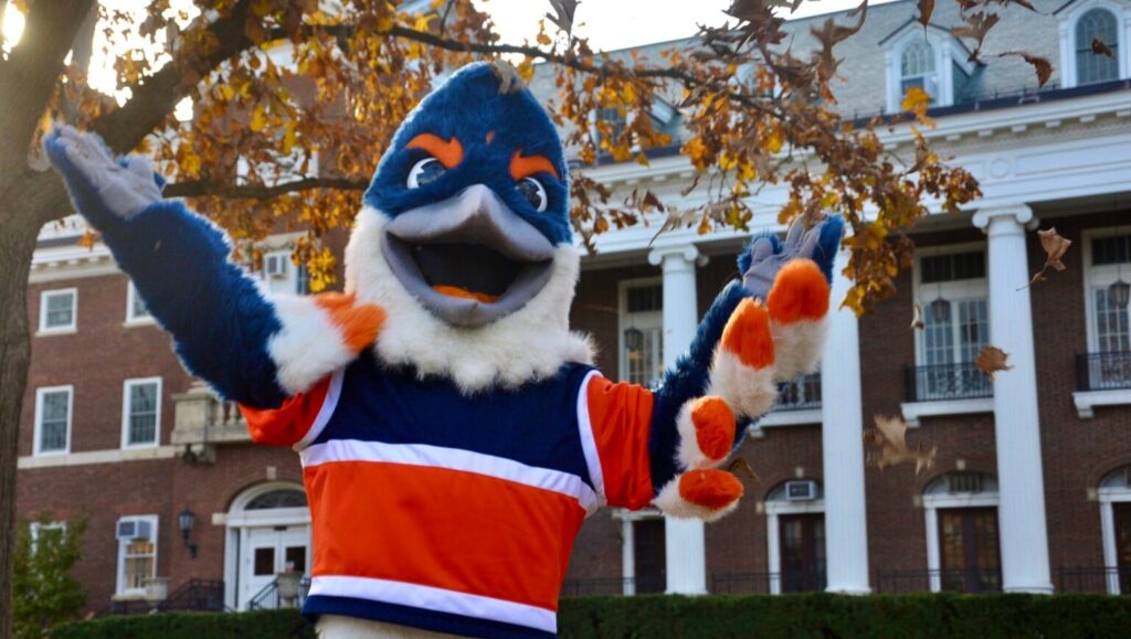 The Belted Kingfisher mascot tossing fall leaves in the air