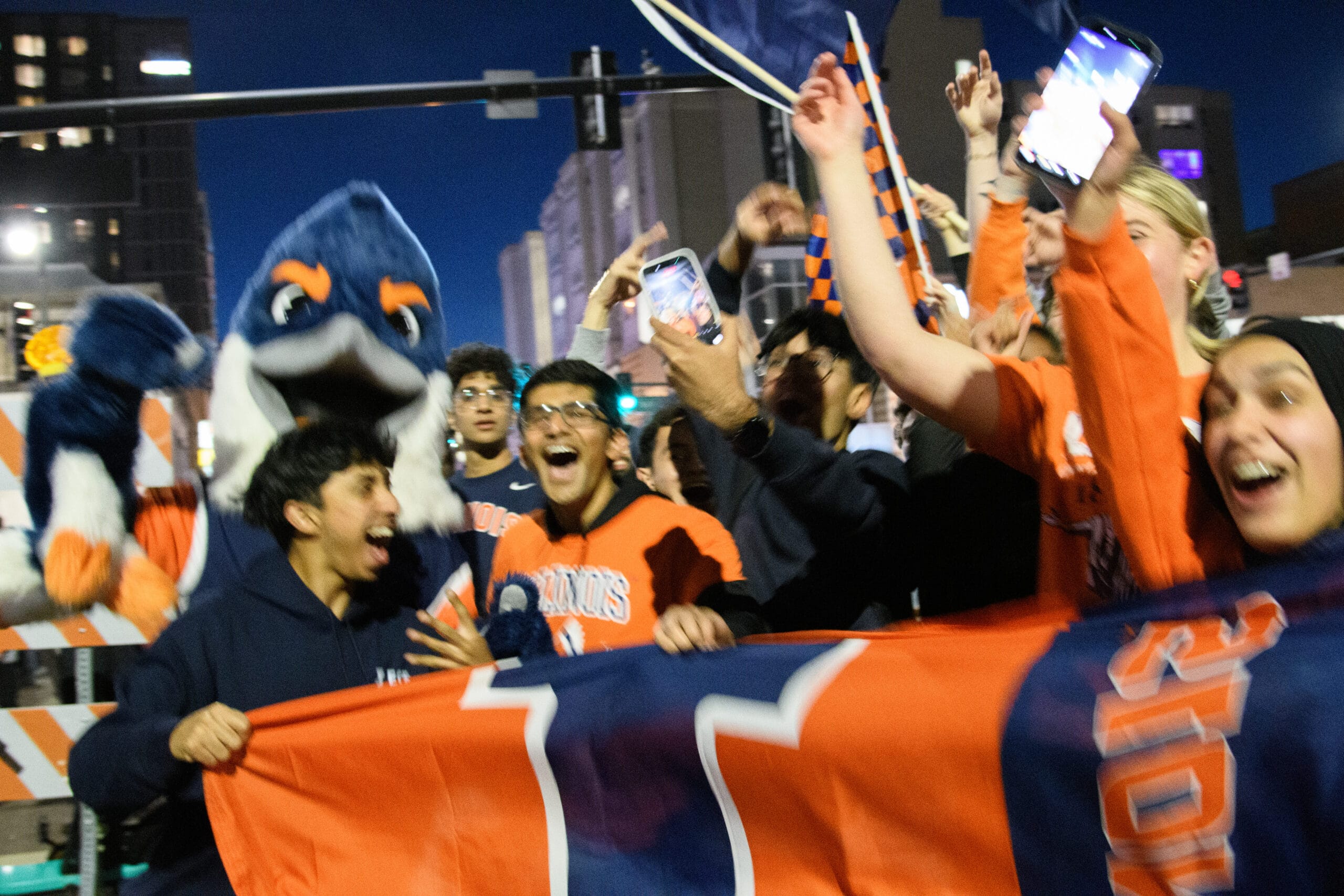 The Belted Kingfisher mascot cheering with a large group of University of Illinois students